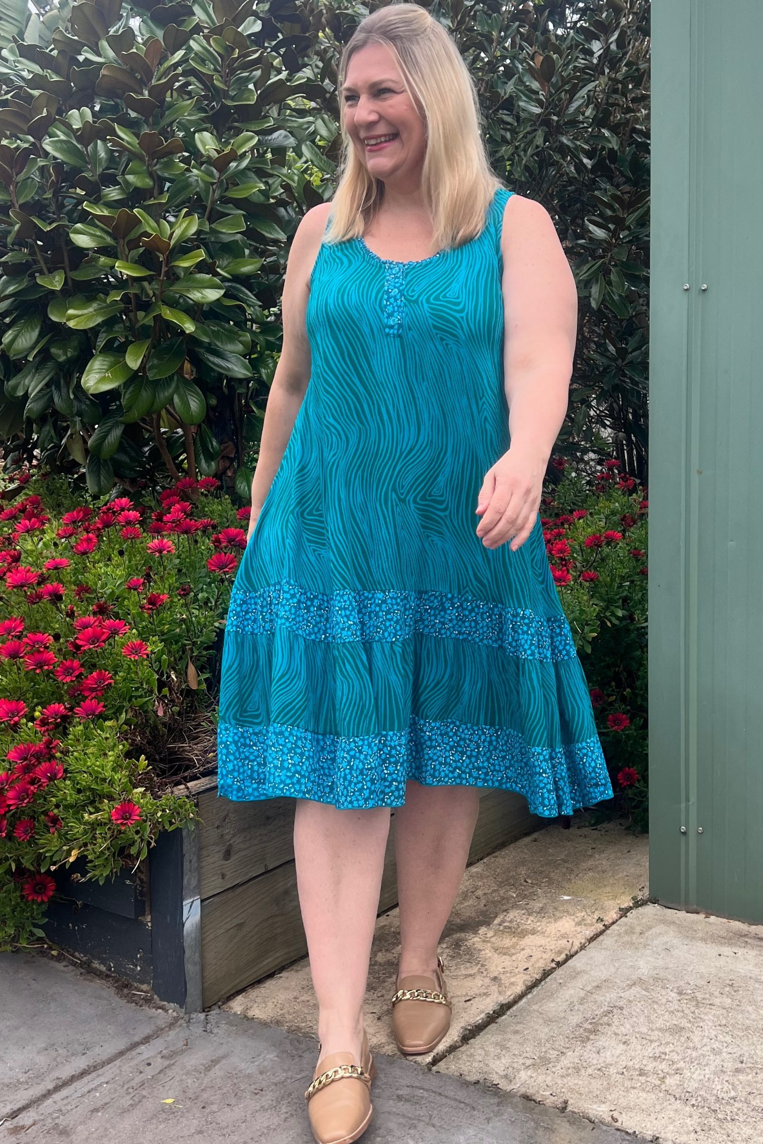 Kita Ku modelling dress Minnie in teal and blue combo printed layer dress , which has no sleeves in a garden setting. 