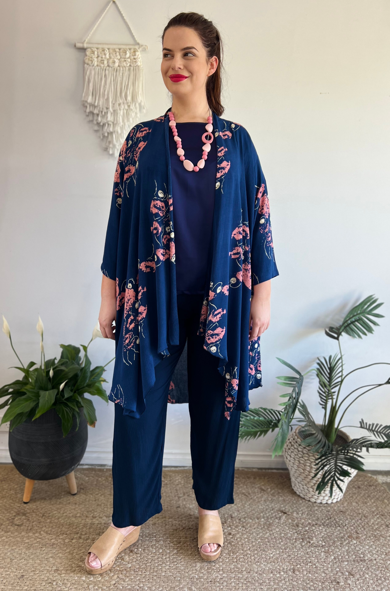 Kita Ku modelling the navy pant kita along with a navy and floral jacket in a retail setting. 