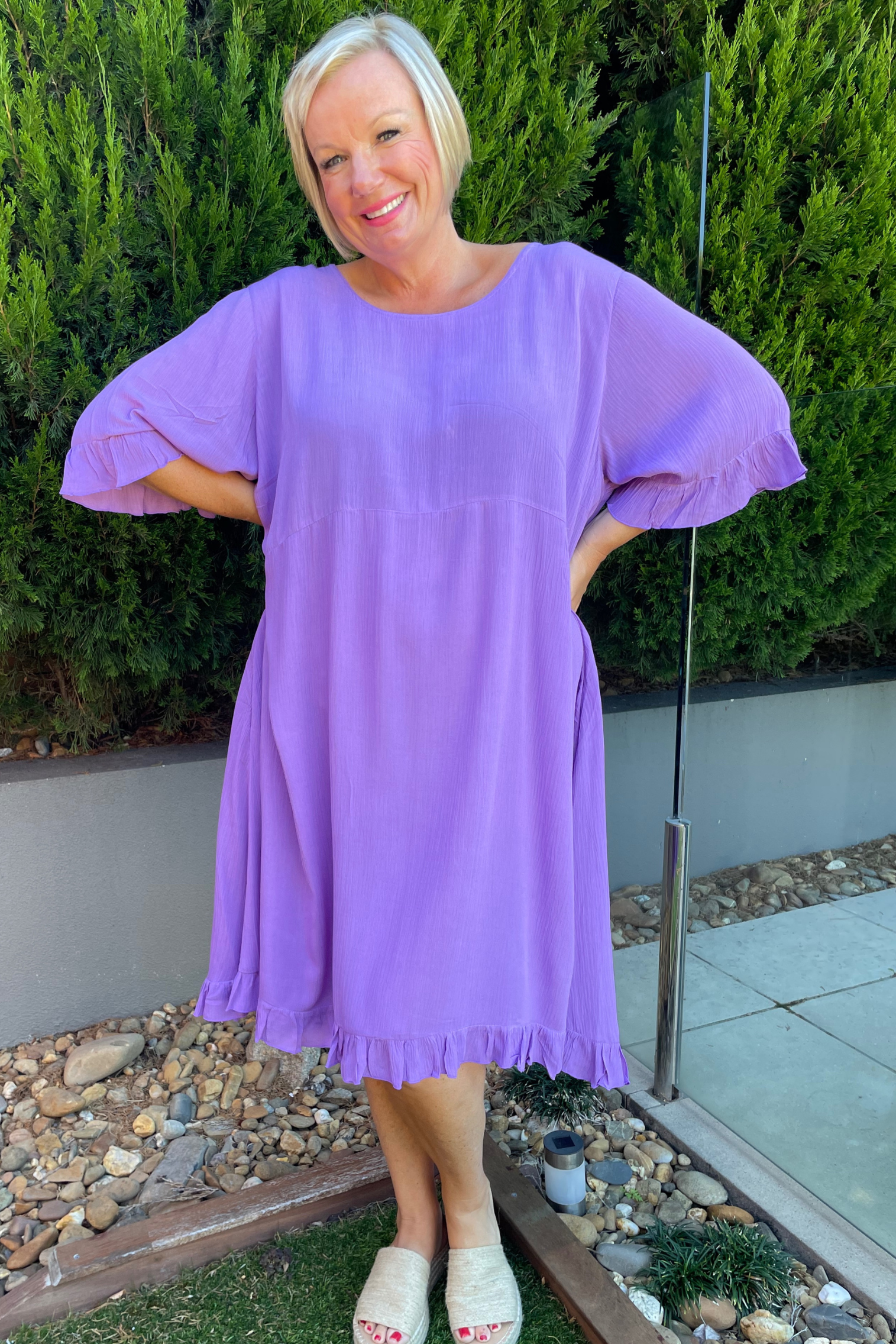 Kita Ku modelling a lilac mauve leonie short sleeve dress by a pool fence