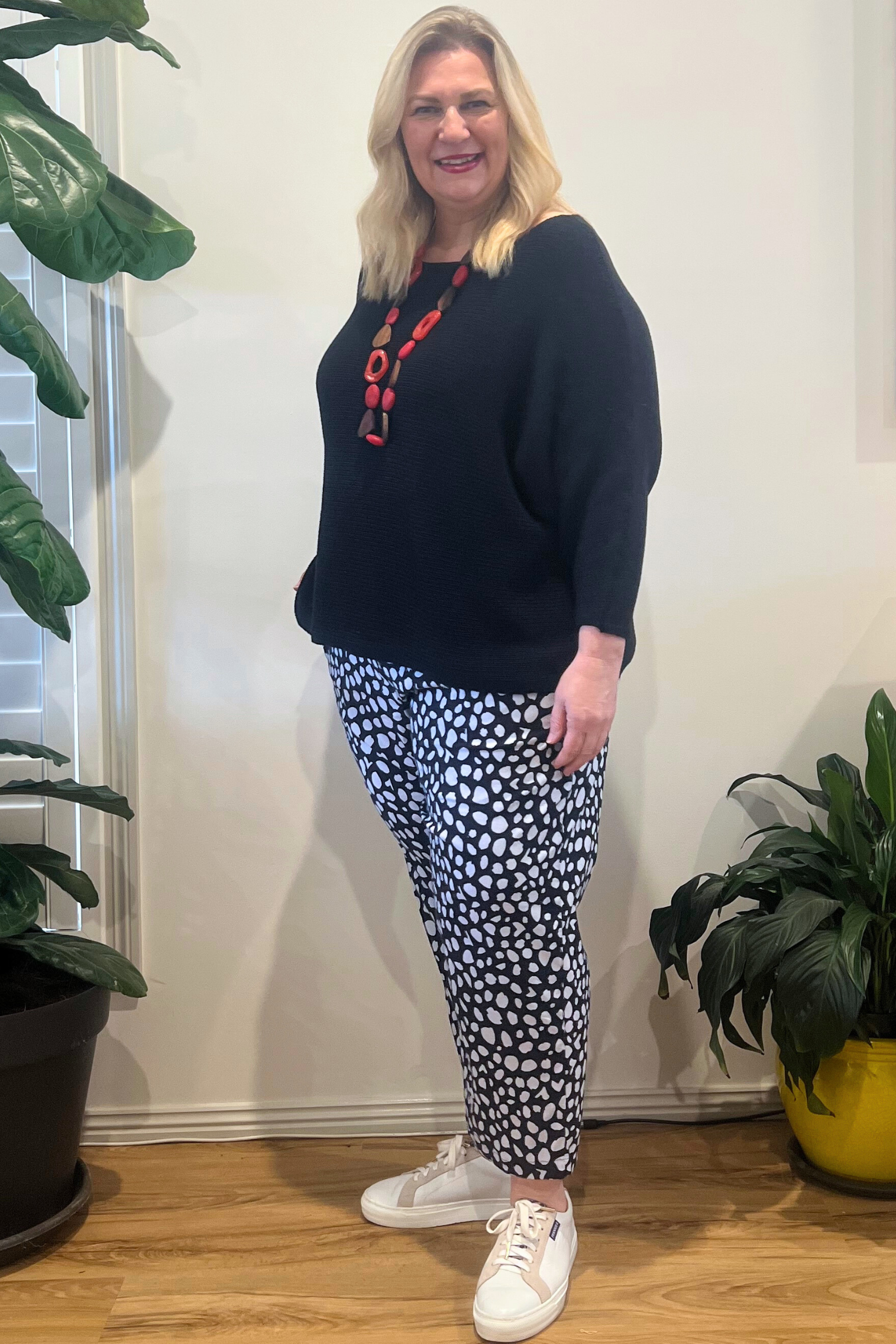 Kita Ku modelling a black and white spotted Pant Port with a black jumper and set indoors. 
