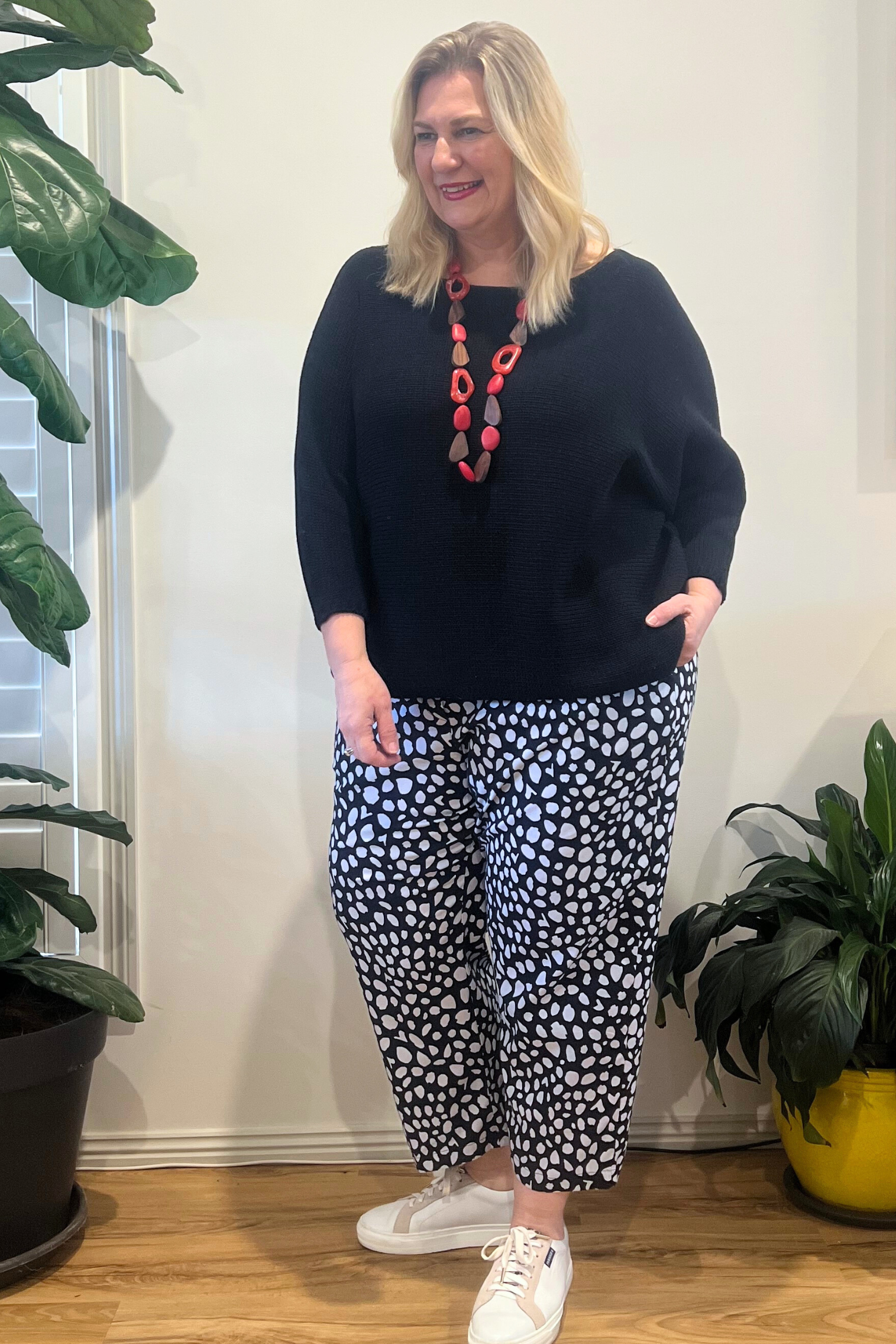 Kita Ku modelling a black and white spotted Pant Port with a black jumper and set indoors.