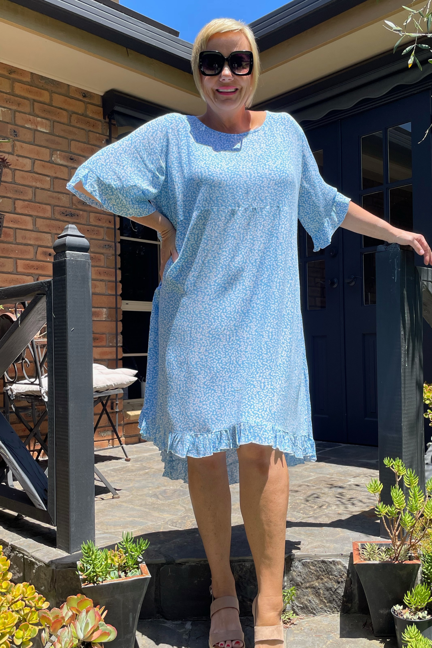 Kita Ku plus size dress Leonie in a pretty soft blue and white holly print, set in a sunny garden. 