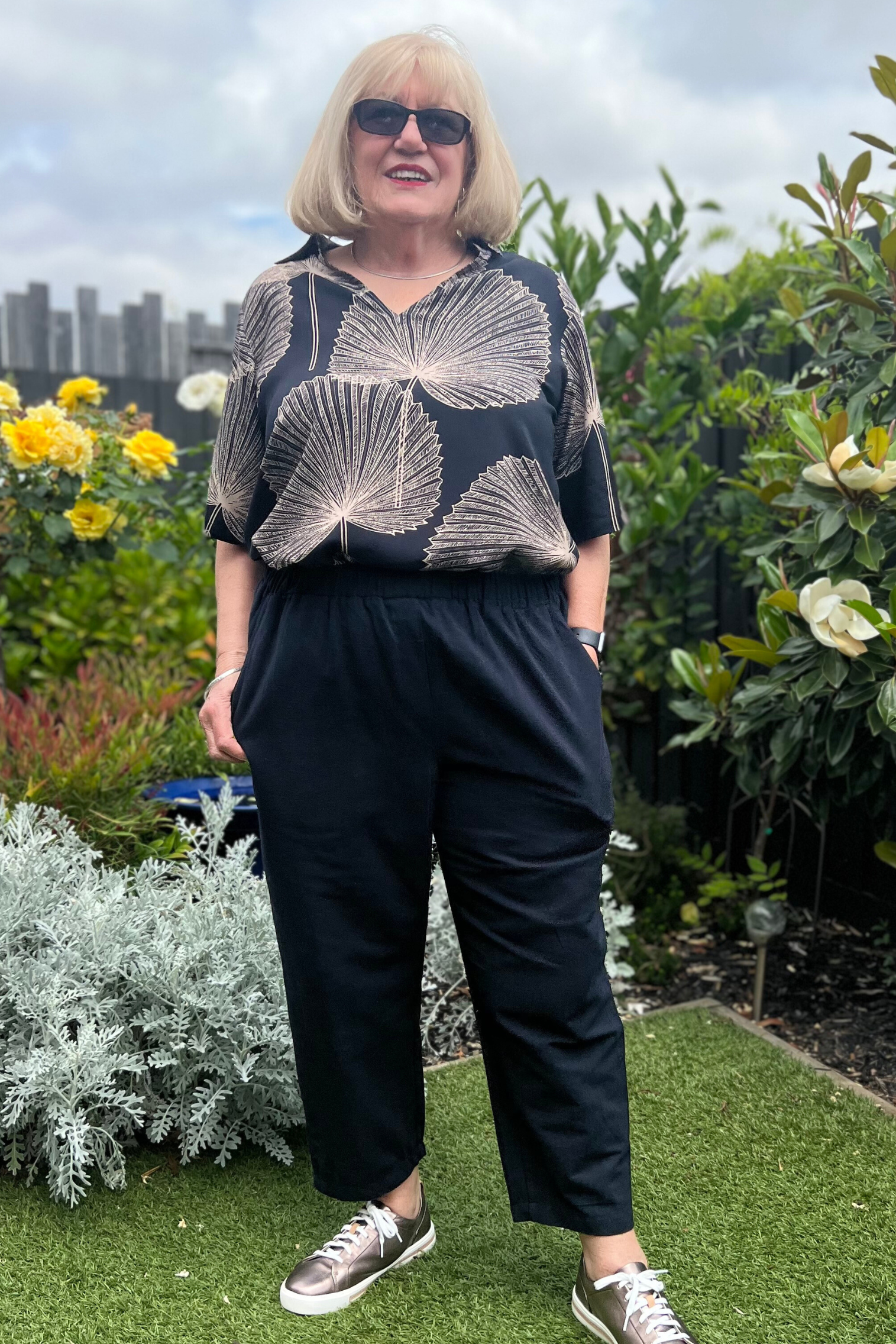 Kita Ku modelling the cotton black pant port with a top rebecca in Paolo print, and set in a sunny garden. 