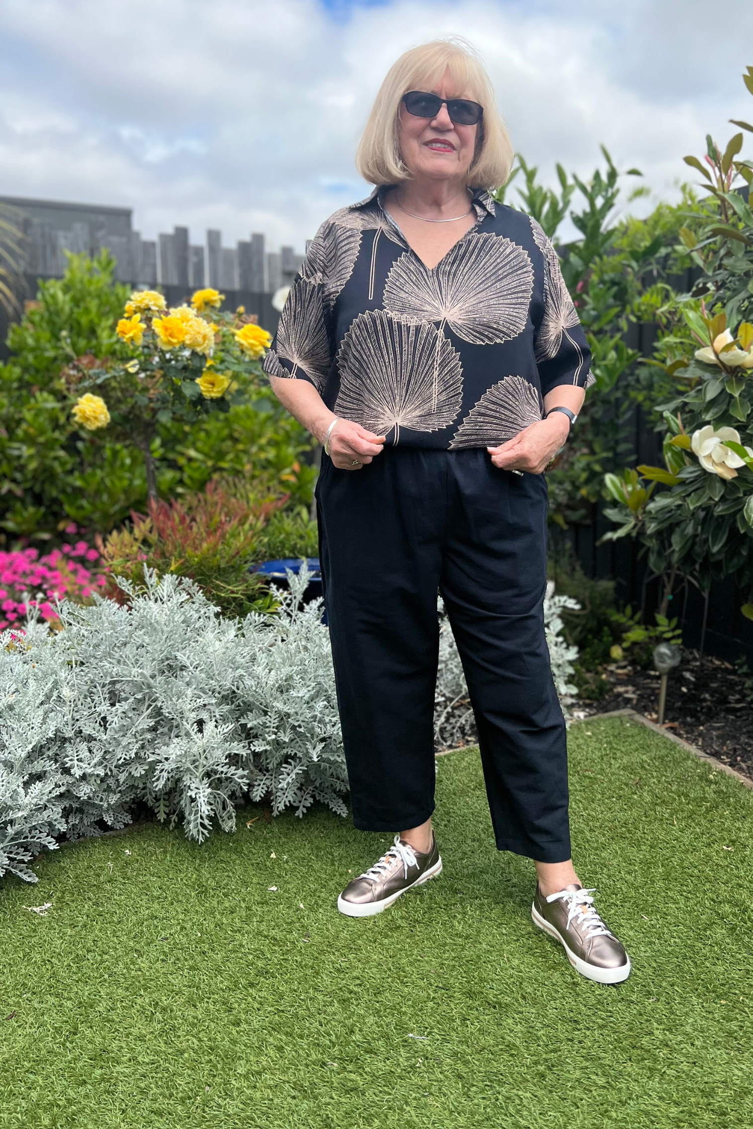 Kita Ku modelling the cotton black pant port with a top rebecca in Paolo print, and set in a sunny garden.